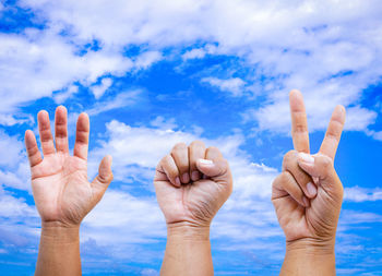 Close-up of human hands gesturing against blue sky