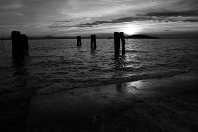 Wooden posts in sea against sky