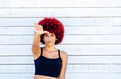 Portrait of beautiful young woman against wall