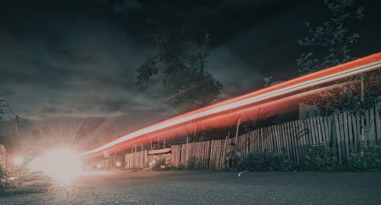 BLURRED MOTION OF ILLUMINATED ROAD AT NIGHT