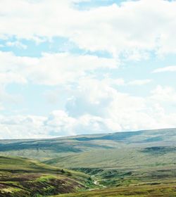 Scenic view of agricultural field against cloudy sky