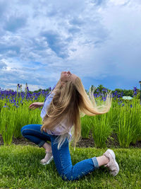 Rear view of woman sitting on field against sky