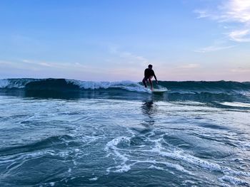 Rear view of woman standing on sea against sky