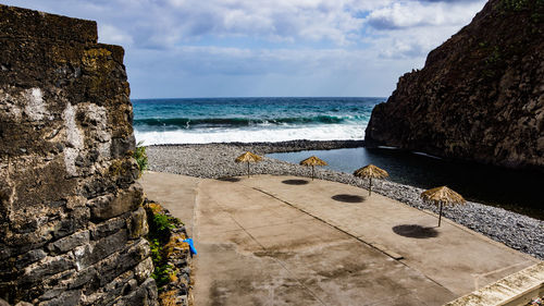 Scenic view of rocks by sea against sky
