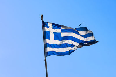 Low angle view of greek flag against clear blue sky
