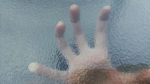 Close-up of hand seen through stained glass window