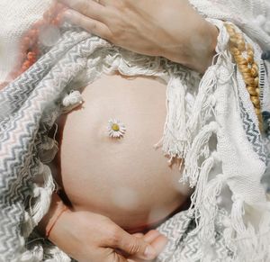 Midsection of pregnant woman with flower on belly