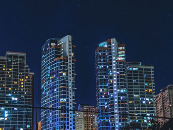 Low angle view of illuminated buildings against sky at night