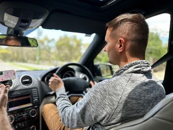 Side view of man sitting in car