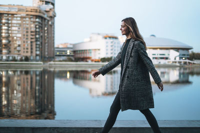 Side view of young woman standing in city