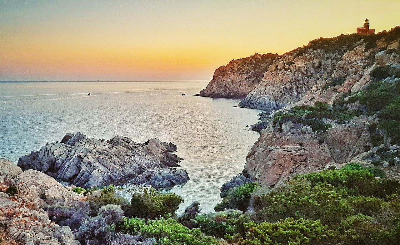 ROCKS ON SHORE AGAINST SKY DURING SUNSET