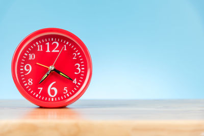 Close-up of clock on table against blue background