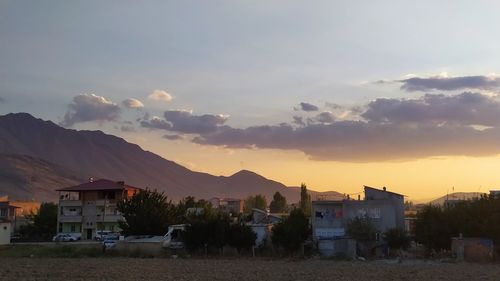 Houses by buildings against sky during sunset