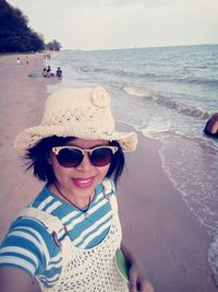 Portrait of smiling young woman on beach against sky