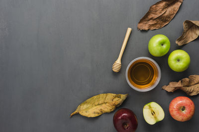 Directly above shot of apples with honey and dry leaves on gray background