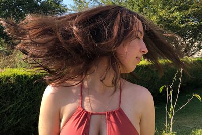 Close-up of woman tossing hair against plants 