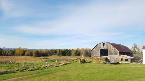 House on field by trees against sky