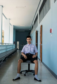 Portrait of young man sitting in corridor of building