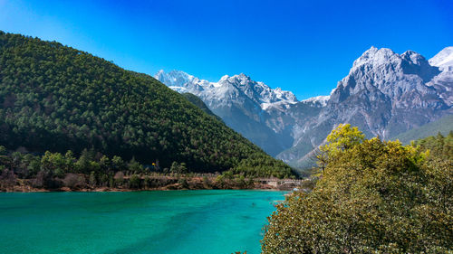 Scenic view of sea and mountains against clear blue sky