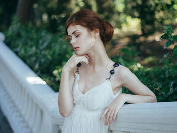 Young woman looking away while sitting outdoors