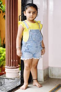 Portrait of cute girl standing against wall