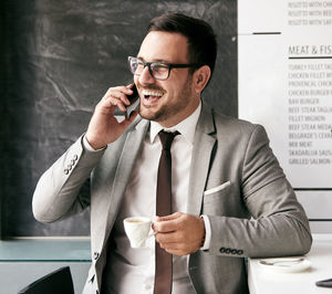 Smiling businessman talking on phone while having coffee