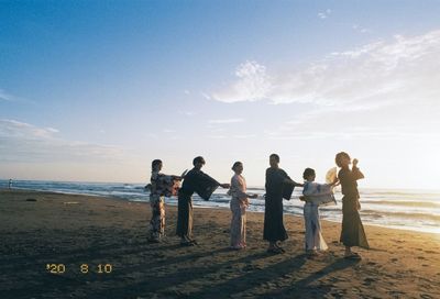 People at beach against sky