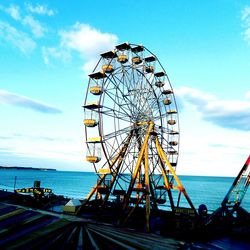 Ferris wheel by sea against sky