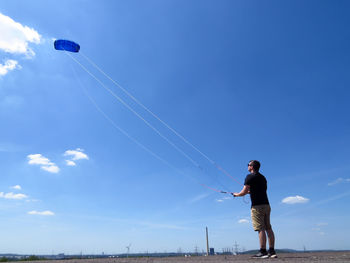 Man kiting against blue sky