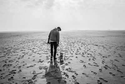 Rear view of man with dog walking at beach