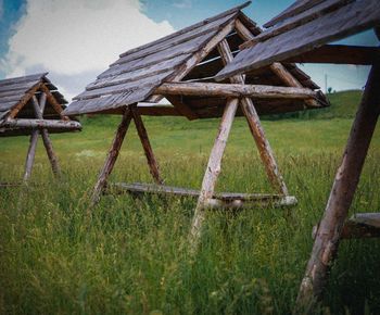Old wooden structure on field against sky