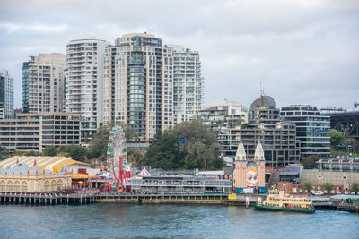 Modern buildings by river against sky in city