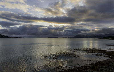 Scenic view of sea against dramatic sky during sunset