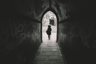 Rear view of woman walking in tunnel