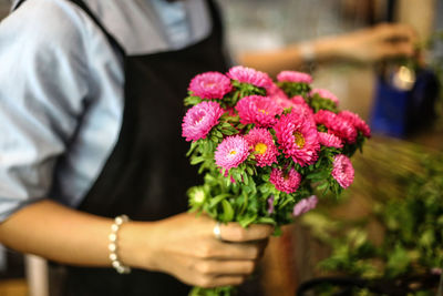 Midsection of vendor holding pink flowers