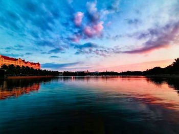 Scenic view of lake against dramatic sky during sunset