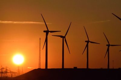 Low angle view of windmills against sky during sunset