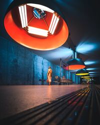 Woman standing at illuminated railroad station