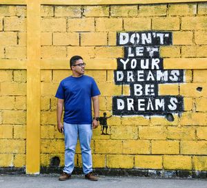 Full length of man standing against yellow wall