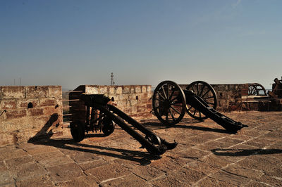 Old metal cart on land against sky