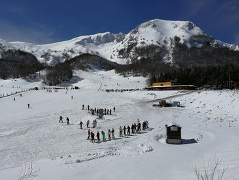 Group of people on snowcapped mountains against sky