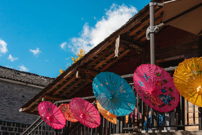 Low angle view of multi colored umbrellas hanging against building