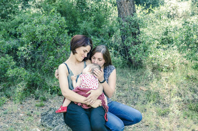 Young woman with baby girl sitting on grass