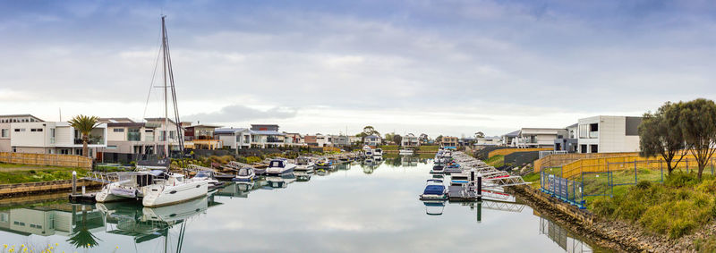 Sailboats moored at harbor against buildings in city