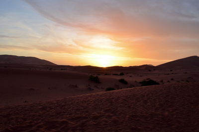 Scenic view of desert against sky during sunset