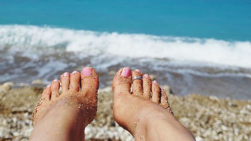 Low section of woman feet covered with sand at beach