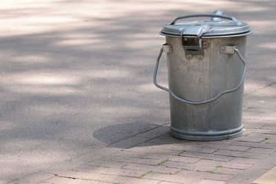 Metal garbage can on sidewalk