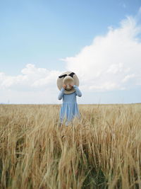 Rear view of woman with arms outstretched on field against sky