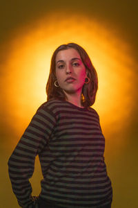 Portrait of young woman standing against yellow wall