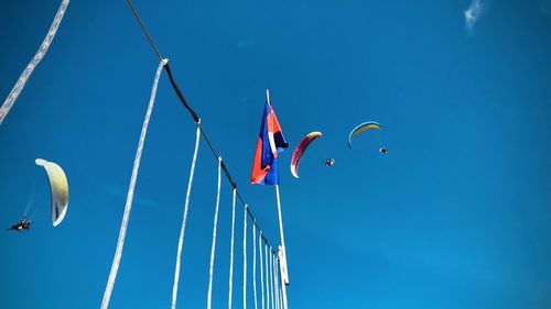 Low angle view of flags against clear blue sky